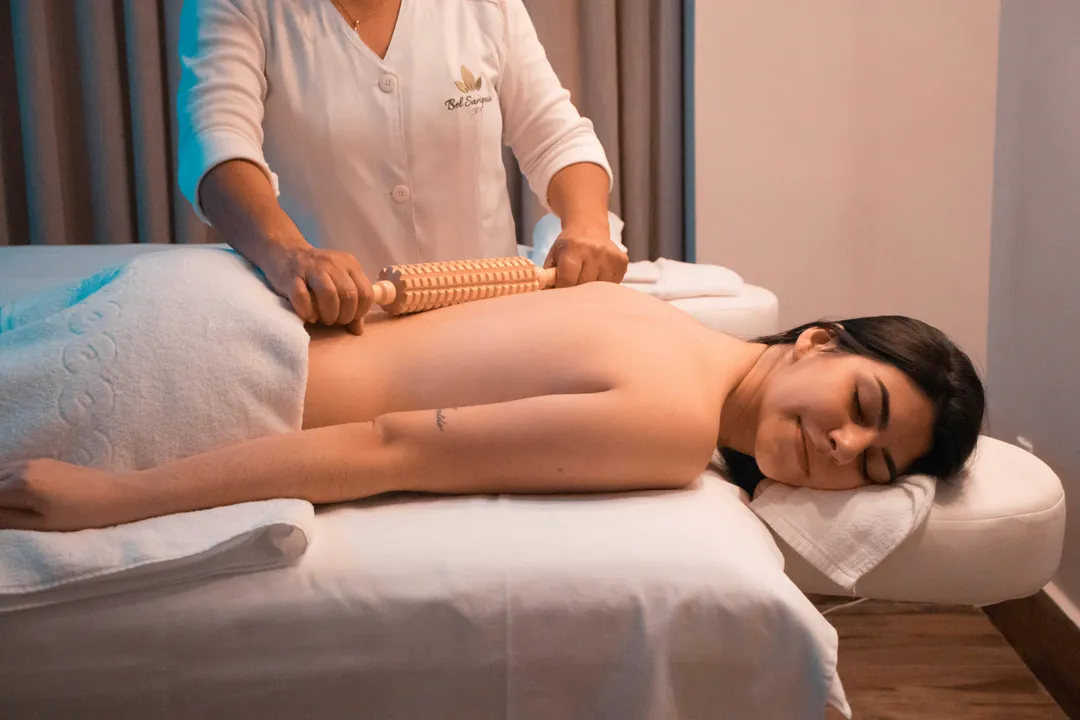 Masseur rollt mit grosser Holznoppenrolle über den Rücken
